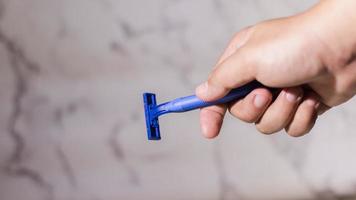 Close up male hand holding a shaver razor on abstack white background