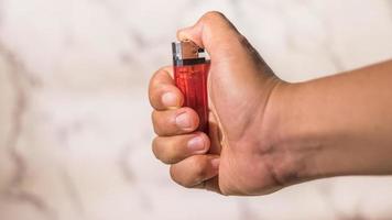 hand of man lighting cigarette lighter against bright background photo