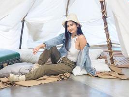 Portrait beautiful young girl woman Asian pretty smile one person alone sitting on chair camping with teble flower in vase lantern red travel trip in front tent freedom relax happy enjoy in vacation photo