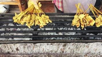satay street food no fogão a carvão - um prato do sudeste asiático que consiste em pequenos pedaços de carne grelhados no espeto e servidos com um molho temperado que normalmente contém amendoim video