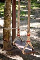 A wooden swing with twine tied to a tree photo