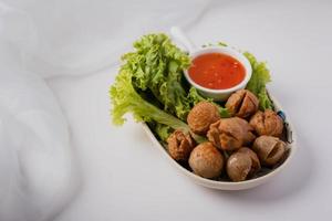 Fried meatballs and dipping sauce on a white background