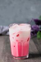 cold pink milk cold drink in clear glass on gray background. Thai milk photo