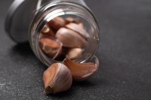 Garlic in a glass jar on a black background photo