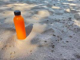 A bottle of orange juice on the beach photo