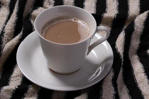 café en una taza de color crema sobre fondo rayado foto