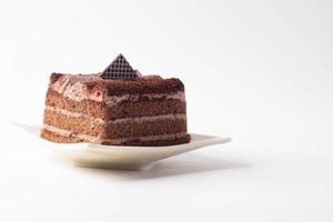The chocolate cake is layered in a plate on a white background. photo