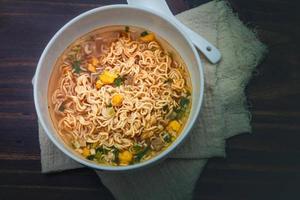 fideos instantáneos tom yum en una taza de cerámica blanca sobre un suelo de madera foto