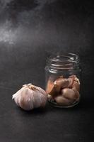 Garlic in a glass jar on a black background photo