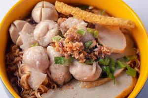 Instant noodles with fish kiew, pork balls and wonton plates. Thai food on a white background. photo