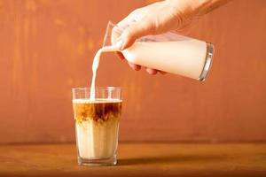 la mano está vertiendo leche en café preparado en estudio con espacio para copiar. foto