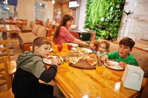 Mother with four childrens eat pizza in pizzeria. photo