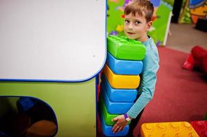 Cute boy playing in indoor play center. Builds with constructor bricks. photo