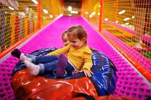 Two sisters sitting in tubing donuts enjoying slides in fun children center. photo