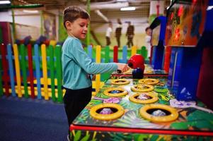 Boy play in hit the hamster game machine at indoor playground. photo