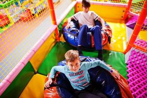 Happy two brothers in tubing donuts enjoying slides in fun children center. photo