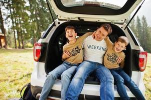 Family at vehicle interior. Father with his sons. Children in trunk. Traveling by car in the mountains, atmosphere concept. photo