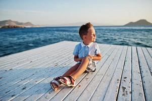 Boy sit at Turkey resort on pier against Mediterranean sea. photo