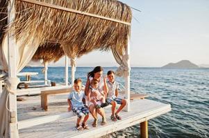 Mother with three kids on Turkey resort sitting bungalow against Mediterranean sea. photo