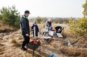 Family barbecuing on a deck in the pine forest. Bbq day with grill. photo