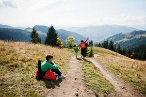 la mujer viaja con un niño. mamá en las montañas. subir a la cima de la montaña con niños. con la mochila subida hasta arriba. foto