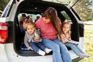 Family at vehicle interior. Mother with her daughters. Children in trunk. Traveling by car in the mountains, atmosphere concept. photo