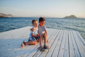 dos hermanos sentados en el resort de turquía en el muelle contra el mar mediterráneo. foto