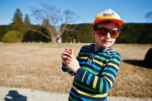 Boy in cap and sunglasses making photo by phone in Lednice park, Czech republic.