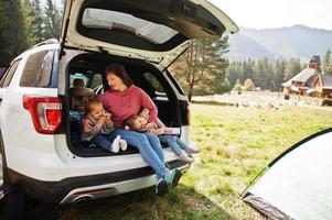 Family at vehicle interior. Mother with her daughters. Children in trunk. Traveling by car in the mountains, atmosphere concept. photo