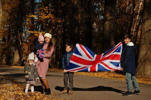 National holiday of United Kingdom. Family with british flags in autumn park.  Britishness celebrating UK. Mother with four kids. photo