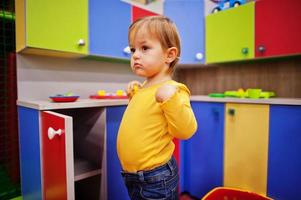 Cute baby girl playing in indoor play center. Kindergarten or preschool play room. In the children's kitchen. photo