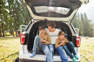 Family at vehicle interior. Father with his sons. Children in trunk. Traveling by car in the mountains, atmosphere concept. photo