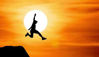 Silhouette of an athlete jumping on a rocky cliff photo