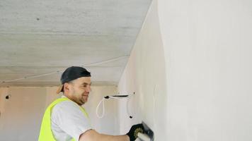 The master of repair of apartments aligns walls with plaster. Painting and plastering works on construction sites. video