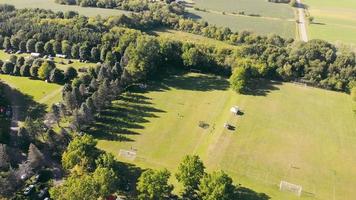 campo de fútbol en el campo, entre la zona boscosa en un día soleado. vista aérea desde un dron del campo de fútbol local en una ubicación rural, con un espeso bosque alrededor del área. concepto de destino video