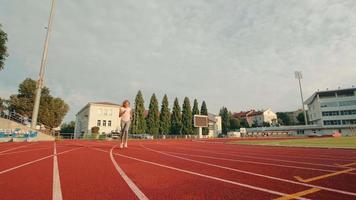 atleta che finisce lo sport e corre verso il traguardo. ferma la donna corridore e fai respiri profondi e respira in modo uniforme. correre in uno zaino allo stadio. video