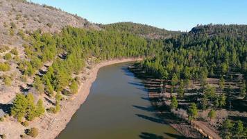 naturskön utsikt över santa fes sjö nära williams, arizona, usa. Flygfoto från drönare av lugn reservoar med röda sandstenstränder, omgiven av skog med trädbevuxna kullar vid horisonten. begreppet landskap video