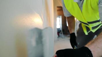 travaux de réparation dans la chambre. un ouvrier du bâtiment applique du mastic sur le gros plan du mur. video