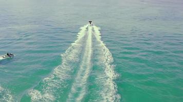 Speed-Motorboot, das auf blauem Meerwasser segelt und im Sommer weiße Strudelspuren hinterlässt. Luftbild von oben auf Schnellbootwege auf der Meeresoberfläche in der Bucht. konzept der wasseraktivitäten