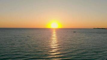 farbenfroher Sonnenuntergang über Meerwasser mit Wellen, die an der Küste rollen, und Reflexion des wolkenlosen Himmels. Panoramablick auf die orangefarbene Sonne, die über dem Horizont untergeht, mit malerischer Meereslandschaft. Konzept der Meereslandschaft video