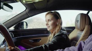 The passenger of the Bentley, a girl, has turned on the music on the control panel and is dancing. Background,mountains,trees are green video