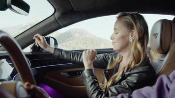Passenger girl dancing in the front seat of a Bentley.Background,mountains,derevya video
