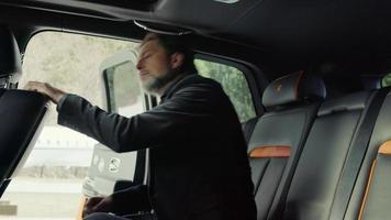 A passenger is sitting in the back seat of a Rolls-Royce on the airport runway video