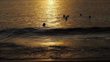 belo pôr do sol com silhuetas de pessoas apreciam o oceano. video