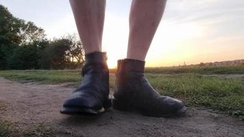 Dancing male legs in old shoes at sunset in summer in nature.