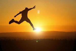 The silhouette of a man is jumping forward. The concept of clawing through hurdles photo