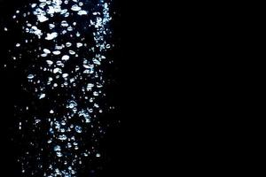 Water bubbles isolated on black background, close up view. Rippling liquid surface, an abstract background for overlays design photo