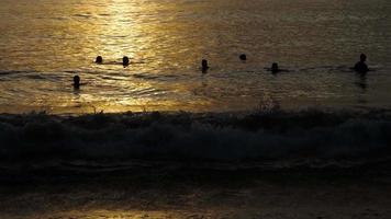 bel tramonto con sagome di persone che si godono l'oceano. video