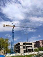 edificio en construcción, grúa bajo cielos azules y nubes. foto