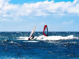 Two windsurfers blue water bright sun blue sky photo